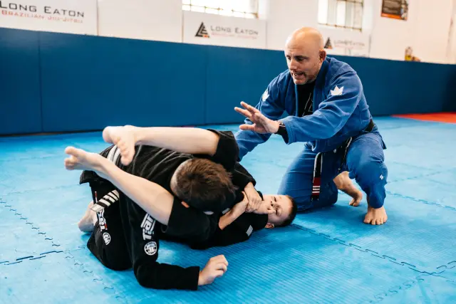 Instructor guiding two junior students through a ground position drill