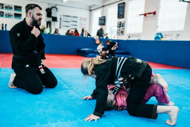 Instructor supervising two junior students during controlled sparring